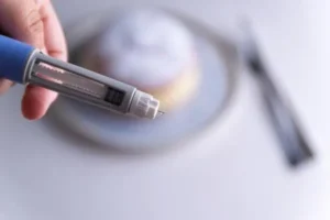 Close-up of a hand holding a syringe-like device with a fine needle.