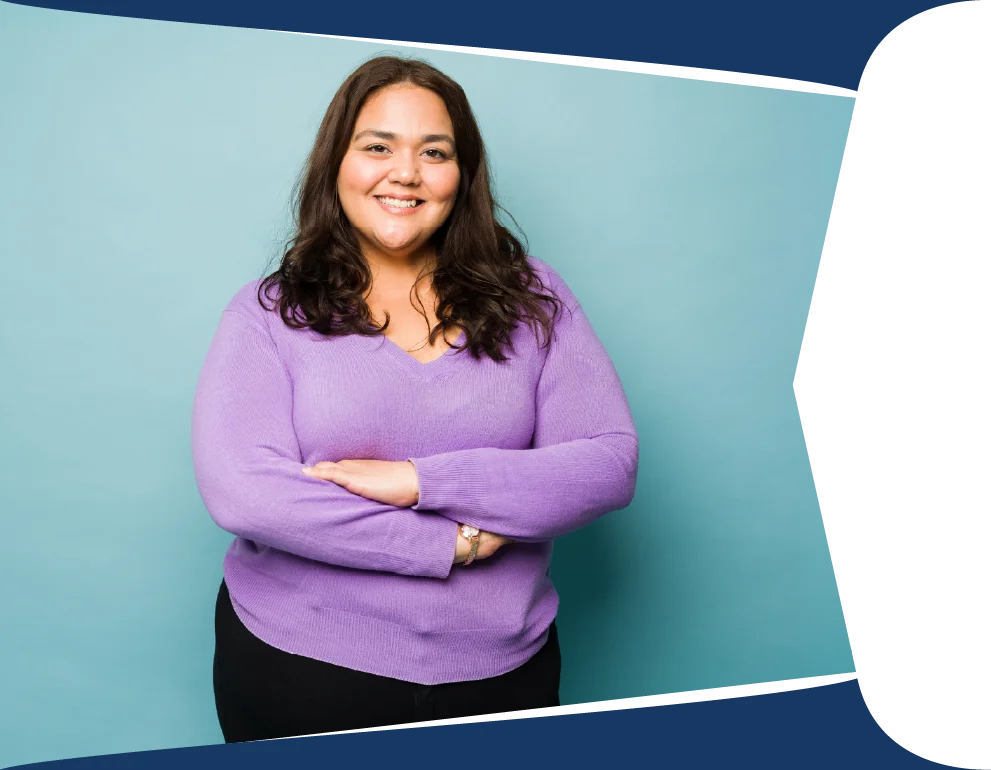 Smiling woman with dark hair in a purple sweater, arms crossed, standing against a teal backdrop.