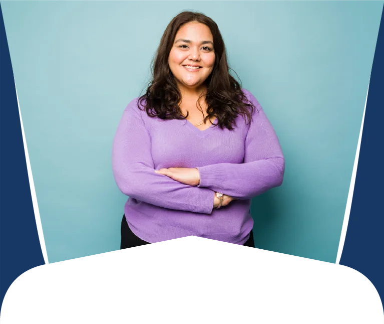 Smiling woman with dark hair in a lavender sweater, arms crossed, standing against a teal backdrop.