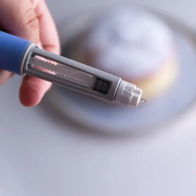 Hand holding a medical lancing device with a tiny needle extended for a finger-prick blood sample readied for testingstopped at the end of the device.